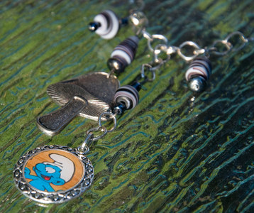  A Smurf image was encased in an ornate frame using resin. The Smurf and cogumelo charm are accented b