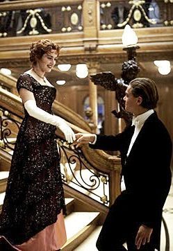 First couple who passes Jack and bows to him downstairs before dinner. What's the colour of woman's dress?