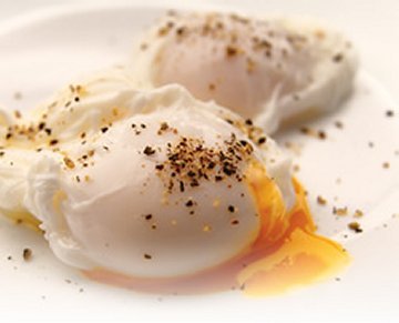  What is the function of adding vinegar to the water when poaching an egg?
